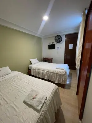 a hotel room with two beds and a clock on the wall at Misky Illari Hospedaje in Ica