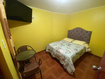 a small bedroom with a bed and a table at Churin Hostal J&D in Churín