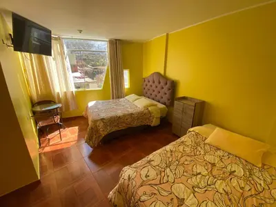 a hotel room with two beds and a television at Churin Hostal J&D in Churín