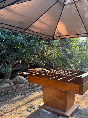 a wooden game table with an umbrella over it at Rosa Estela in Cieneguilla