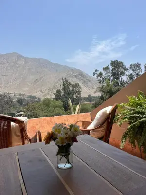 a wooden table with a vase of flowers on a balcony at Rosa Estela in Cieneguilla