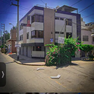 a building on a city street with flowers and a sidewalk at Hospedaje Arco Real in Ica
