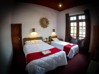 a hotel room with two beds and a window at Casona Santa Catalina Cusco in Cusco