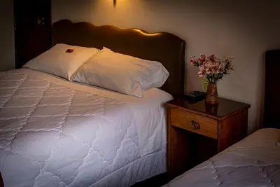 a bedroom with a bed and a vase of flowers on a table at Casona Santa Catalina Cusco in Cusco