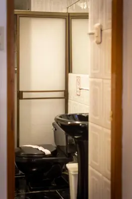 a bathroom with a black toilet and a sink at Casona Santa Catalina Cusco in Cusco