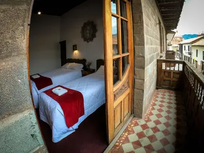 a bedroom with two beds and a balcony at Casona Santa Catalina Cusco in Cusco