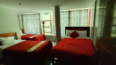a bedroom with two beds with red sheets and a window at Hotel D'Gloria Churin in Churín