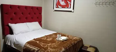 a hotel room with a bed with a red headboard at Hostal Casa Blanca in Ayacucho