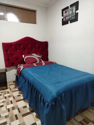 a bedroom with a blue bed with a red headboard at Hostal Casa Blanca in Ayacucho