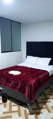 a bedroom with a large bed with a red blanket at Hostal Casa Blanca in Ayacucho