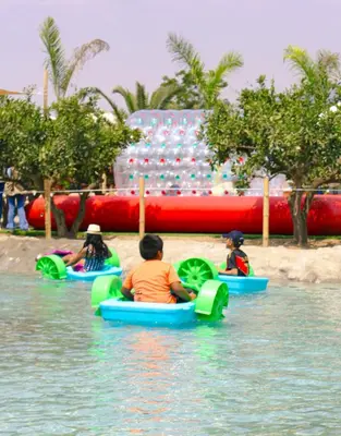 three children are riding in inflatable kayaks in the water at Mandarhemia Club in Huaral