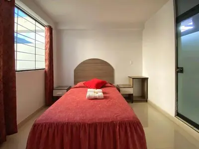 a bedroom with a red bed with two towels on it at Hotel Marabi in Quillabamba