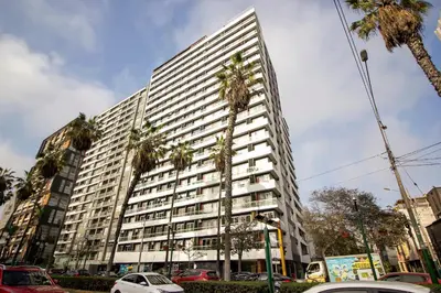 a tall building with palm trees in front of it at View & Pool Barranco loft G15 in Lima