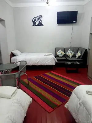 a room with three beds and a rug at Apartamento Privado en San Pedro Cusco in Cusco