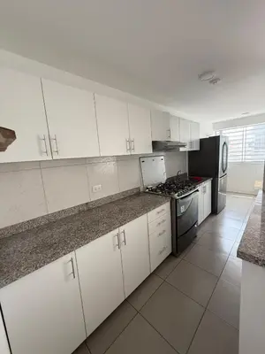 a kitchen with white cabinets and a stove top oven at Departamento San Sebastian in Lima
