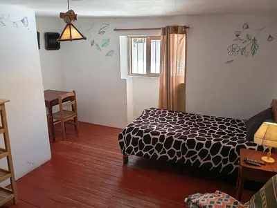a bedroom with a bed and a table and a window at Gatanas House in Cusco