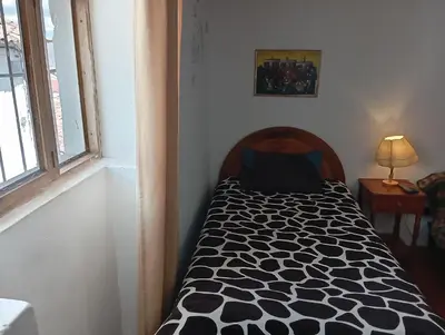 a bedroom with a bed with a black and white comforter at Gatanas House in Cusco