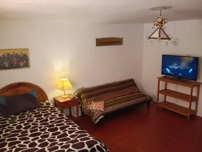 a bedroom with a bed and a tv and a couch at Gatanas House in Cusco