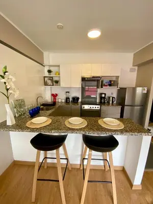 a kitchen with a counter with three bar stools at San Miguel Apartment Vista Mar in Lima