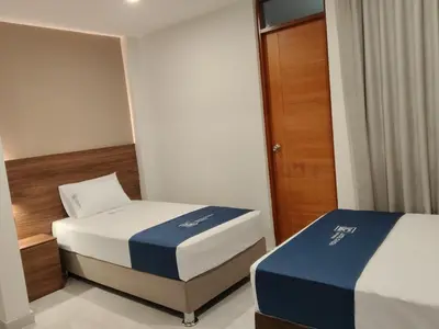 a bedroom with two beds and a wooden door at Luxotel Business Chincha in Chincha Alta