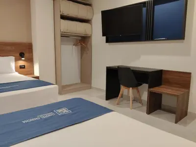 a bedroom with a bed and a desk and a television at Luxotel Business Chincha in Chincha Alta