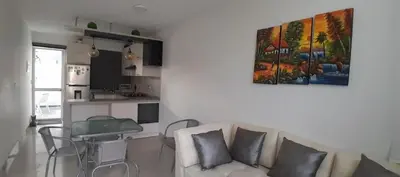 a living room with a white couch and a kitchen at Casa con piscina, terraza y parrilla en Ica in Ica