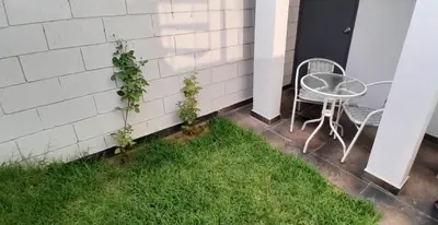 a table and chair on a patio with grass at Casa con piscina, terraza y parrilla en Ica in Ica