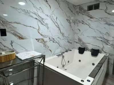 a bathroom with a white tub and marble walls at City Tower Hotel in Lima