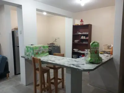 a kitchen with a counter with two chairs and a table at Departamento amoblado y comodo in San Vicente de Cañete