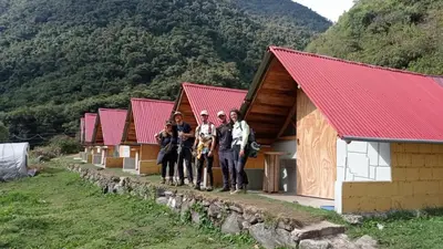 a group of people standing in front of a row of tiny houses at Yawar inka ayllu challhuay in Colcapampa