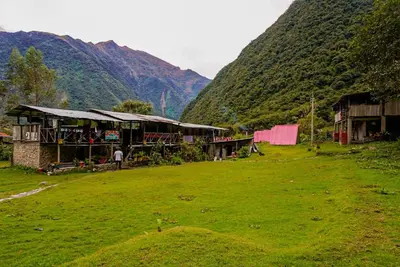a building in a field next to a mountain at Yawar inka ayllu challhuay in Colcapampa