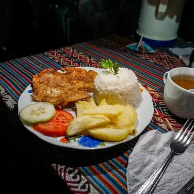 a plate of food with meat and rice and a cup of tea at Yawar inka ayllu challhuay in Colcapampa