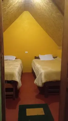 two beds in a room with a yellow wall at Yawar inka ayllu challhuay in Colcapampa