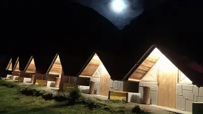a building at night with the moon in the sky at Yawar inka ayllu challhuay in Colcapampa