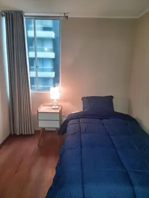 a bedroom with a blue bed and a window at Departamento con Vista al Mar in Lima