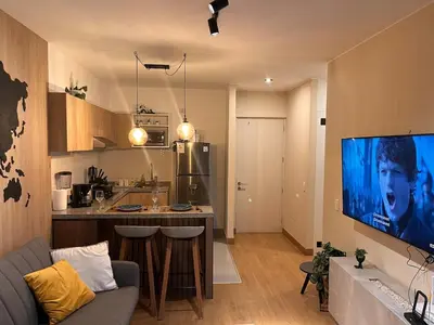 a kitchen and a living room with a large screen tv at Tempo Moderno Departamento in San Antonio