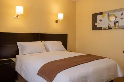 a bedroom with a large bed with white sheets at El Marquez Huancayo in Huancayo