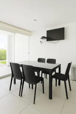 a dining room table with chairs and a television on a wall at Departamento con Jacuzzi privado y acceso directo al mar in Asia