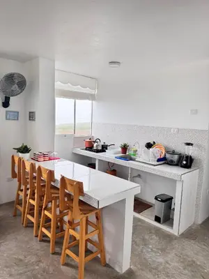 a white kitchen with a table and chairs in it at Departamento en Chancay con Vista al Mar y cerca al Megapuerto