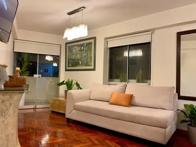 a living room with a couch with an orange pillow on it at Cozy and Centric Flat with Great View and Parking in Lima