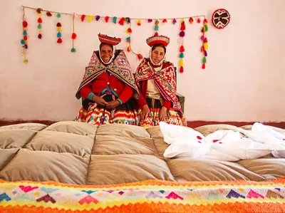 two people sitting on top of a bed at hotel turismo vivencial pallay lliclla in Urubamba