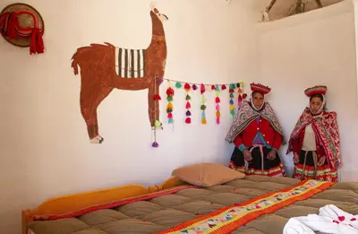 two women in a bedroom with a bed and a horse on the wall at hotel turismo vivencial pallay lliclla in Urubamba