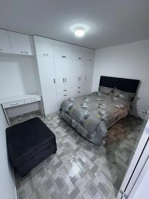 a bedroom with a bed and a ottoman at Mini Departamento in Lima