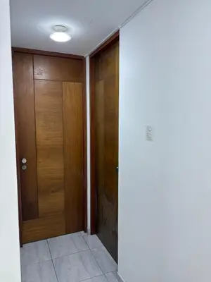 a hallway with two wooden doors in a house at Mini Departamento in Lima