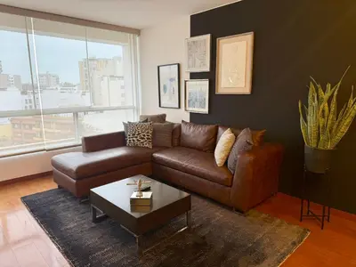 a living room with a brown couch and a coffee table at Departamento Ricardo Palma in Lima