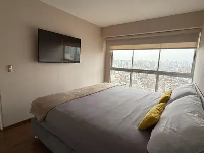 a bedroom with a bed with a television on the wall at Departamento Lock in Lima