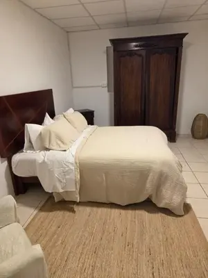 a bedroom with a large bed with white sheets at tiki house in Lima