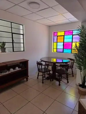a dining room with a table and stained glass windows at tiki house in Lima