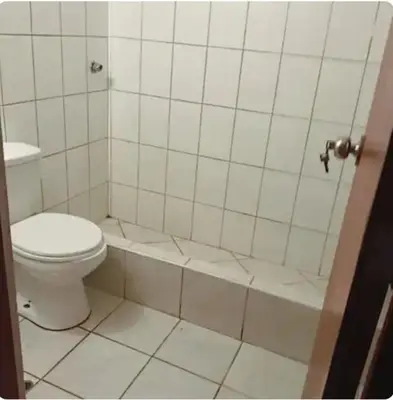 a white tiled bathroom with a toilet and a tub at Departamento minimalista in Lima