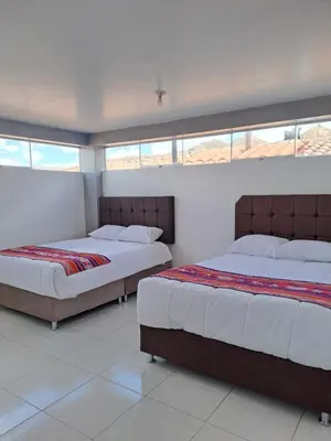two beds sitting in a room with windows at Nina's House in Cusco